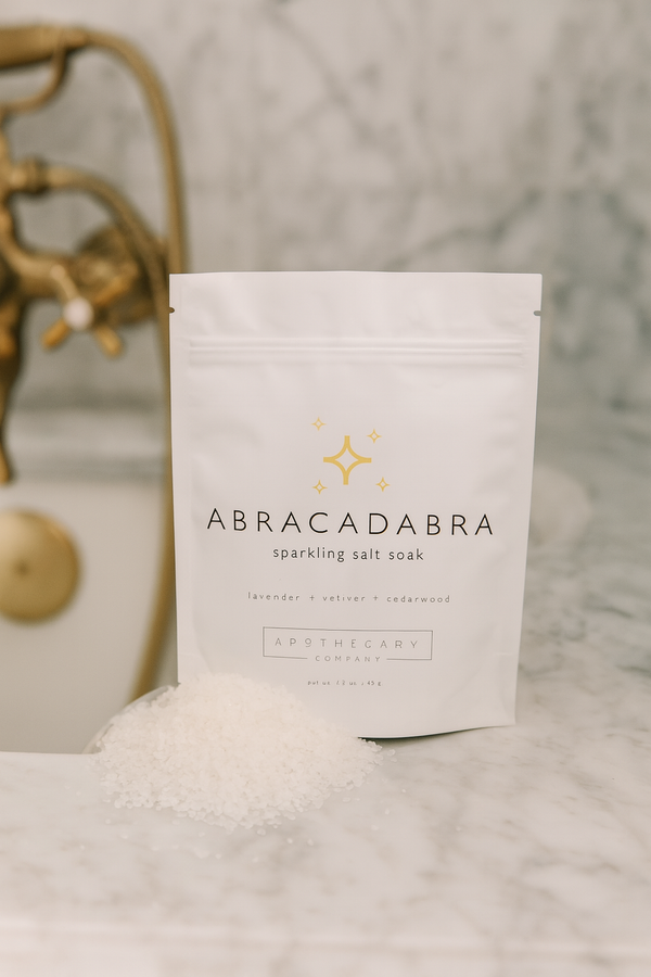 Abracadabra sparkling salt soak packaging on a marble surface with decorative elements.