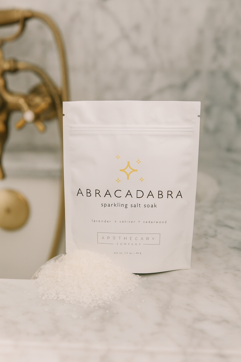 Abracadabra sparkling salt soak packaging on a marble surface with decorative elements.