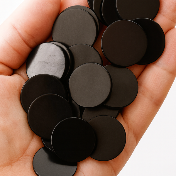 Hand holding a pile of black round objects against a white background